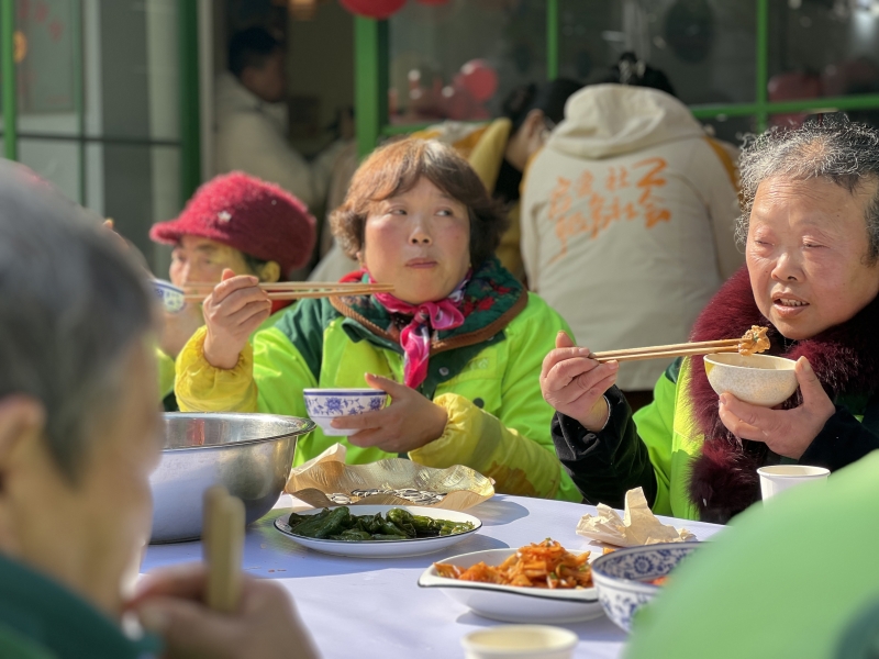 图为正在吃长桌宴的户外劳动者们