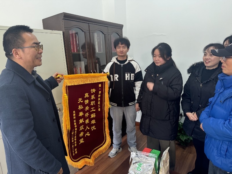 图为困难职工将锦旗送到总工会领导手里