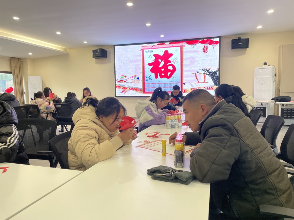 图为职工（农民工）同子女参与制作窗花