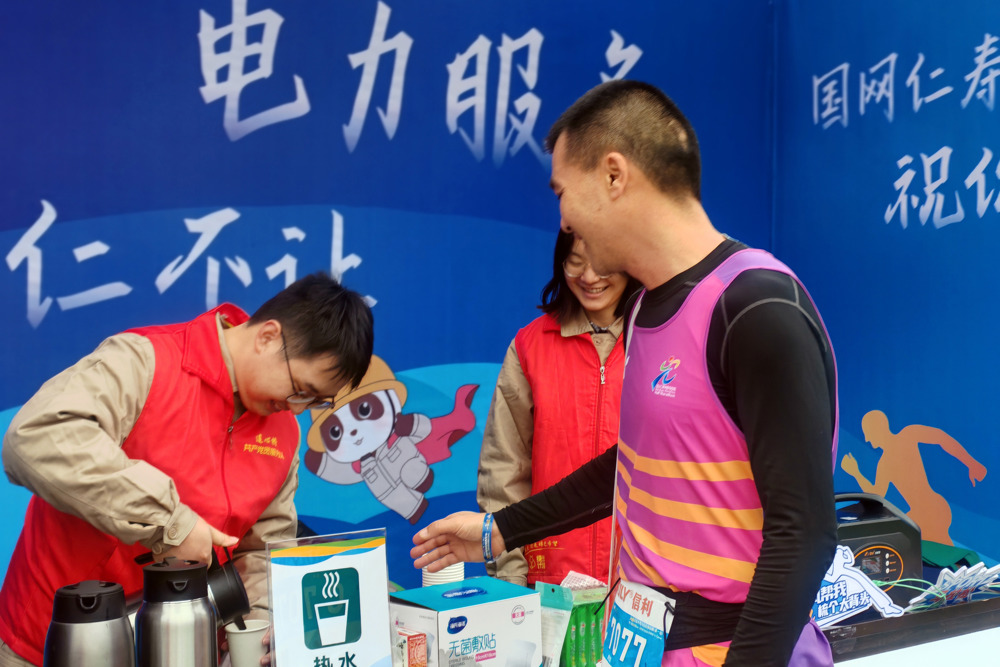 图为电力志愿者为选手加水