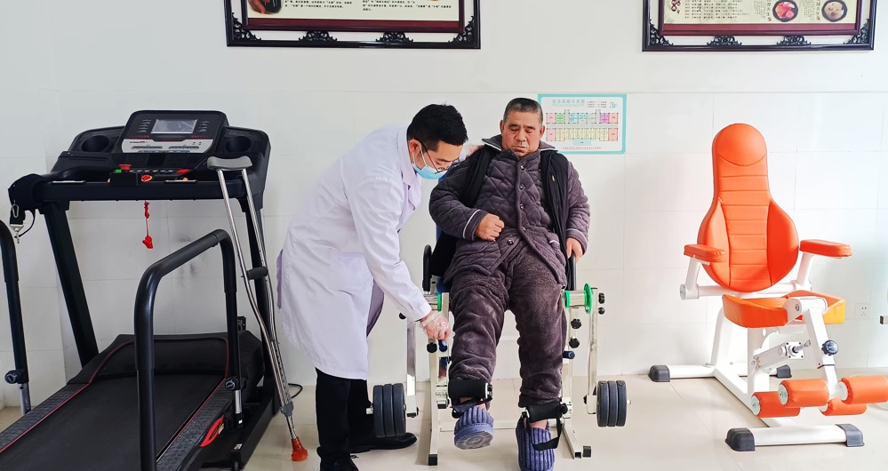 石腊春老人在医护人员的陪伴下进行康复训练