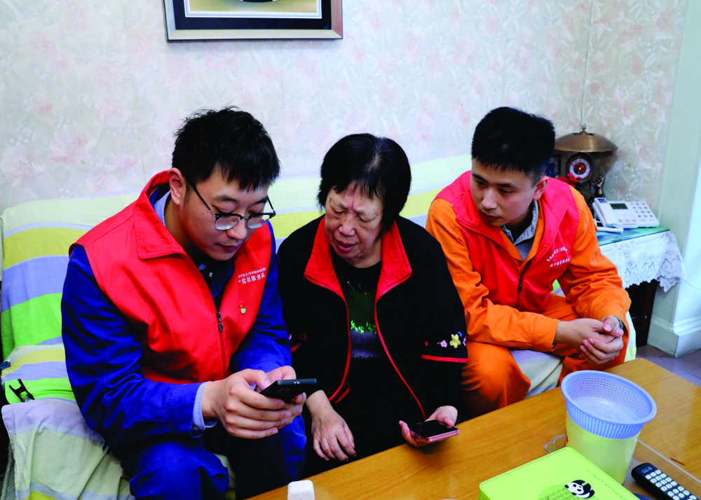“时代楷模”高新连心桥党员服务队队长吴昊（右）为帮扶对象刘婆婆安装并讲解亲老智慧系统使用方法。