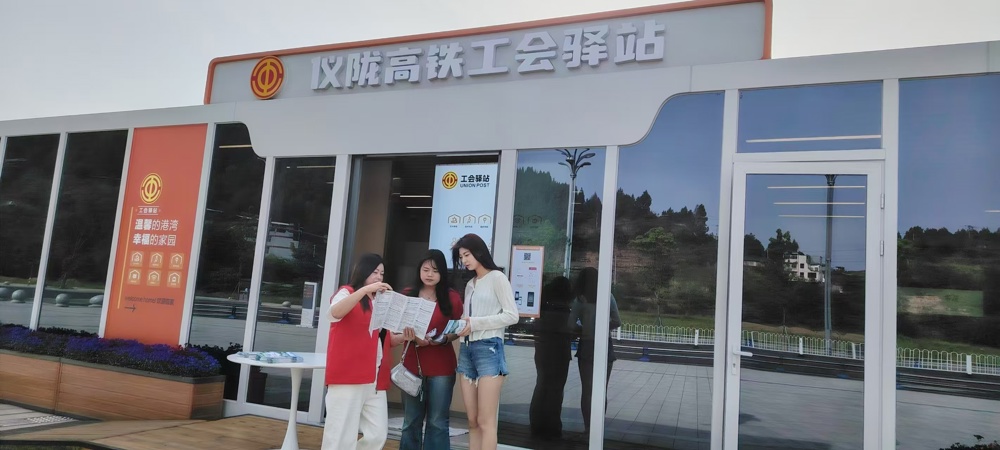 工会工作人员在高铁工会驿站外发放招聘资料