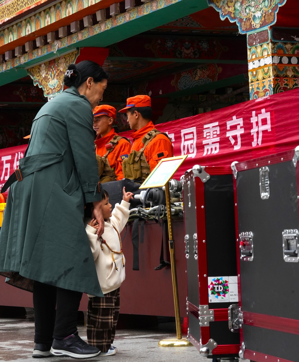 5月19日，在康定情歌广场上，藏区阿妈带着孙女观看森林防火装备