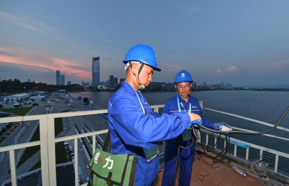 8月15日晚，在天府新区兴隆湖湖滨赛场，国网四川电力工作人员对湖边电源设备进行巡检。 陈翔 摄