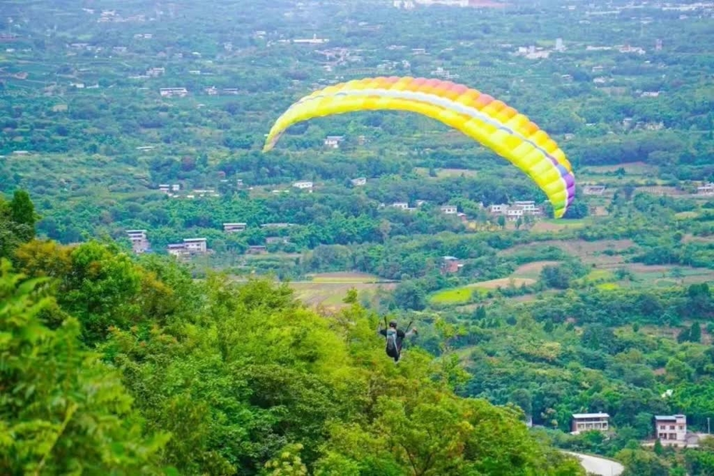 图为游客在滑翔伞基地乘伞翱