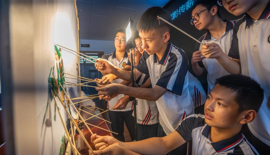 图为学生们在后台操作皮影人物