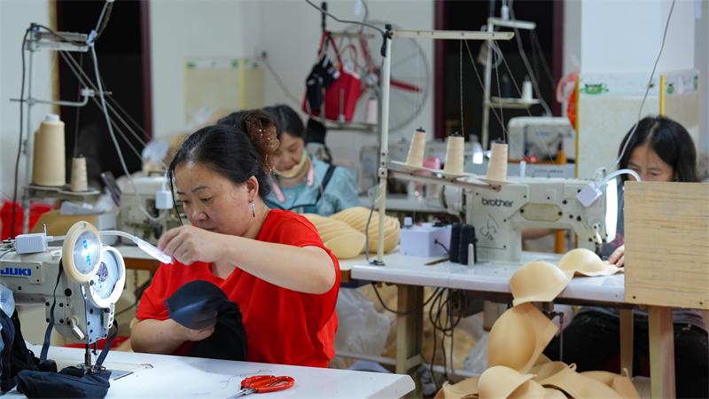 得胜服装内衣厂车间，工人们忙着缝制产品。