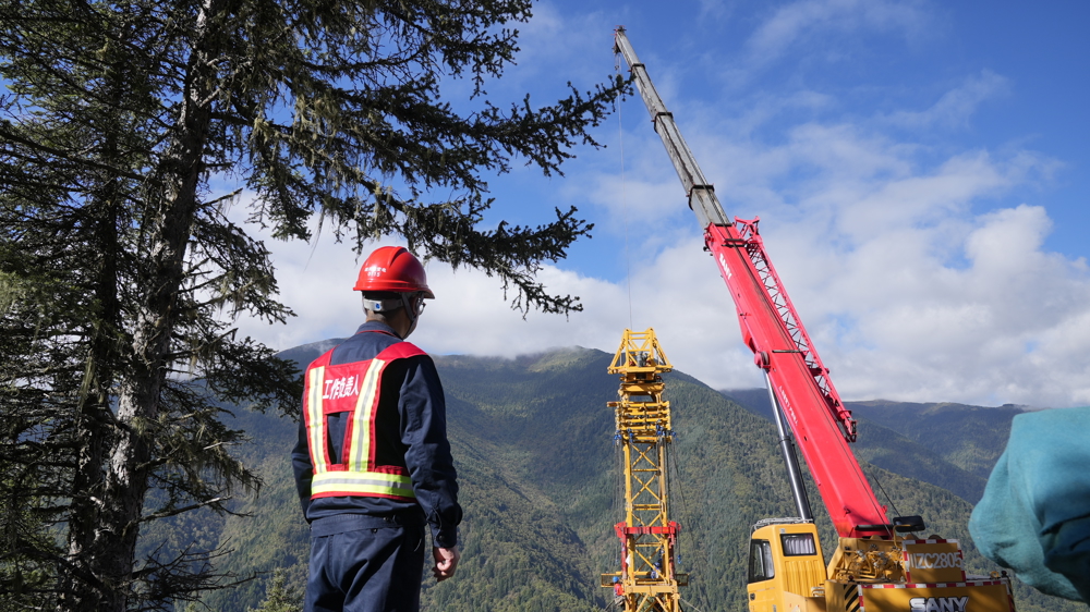 10月1日，在海拔3200余米的阿坝—成都东1000千伏特高压交流输变电工程1标段1R013号塔位，电力工人开展双摇臂抱杆组塔工作。 尤琅  摄