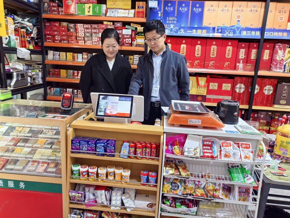 零售户乔莉萌与客户经理蔡玉丁一起查看收银机后台数据