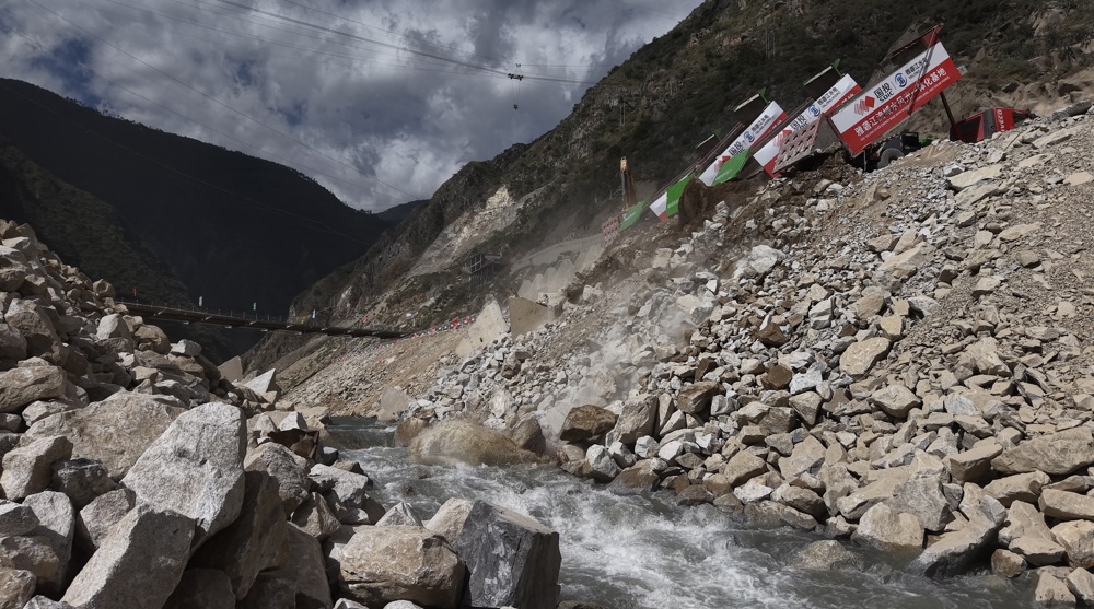 孟底沟水电站数十辆新能源自卸车将石料倾倒入龙口