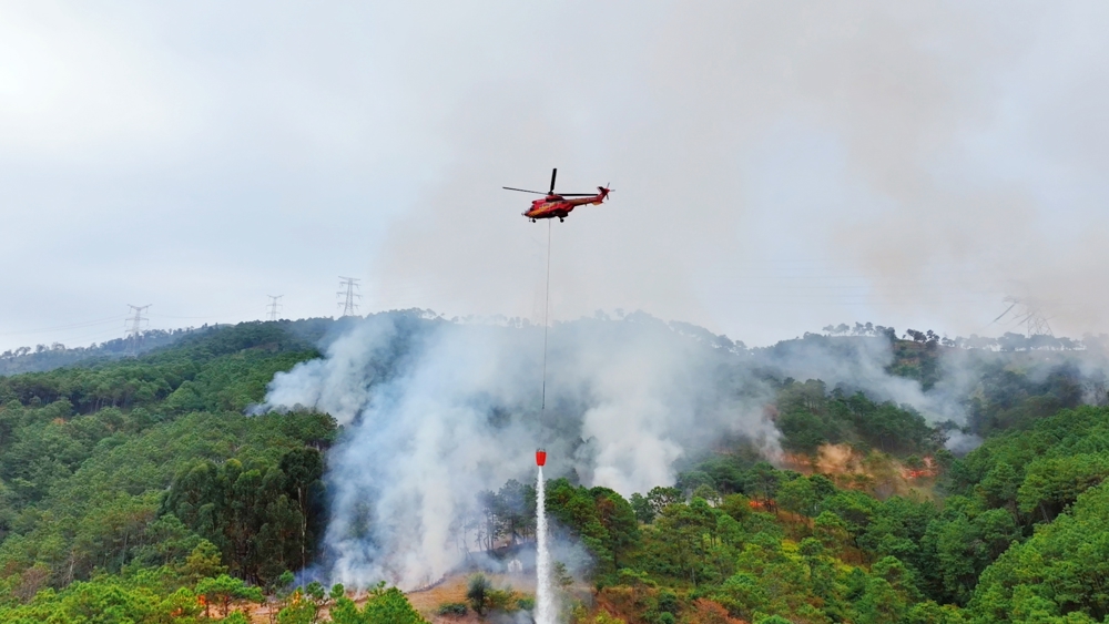 直升机挂载吊桶精准喷洒关键火点。 李威 摄