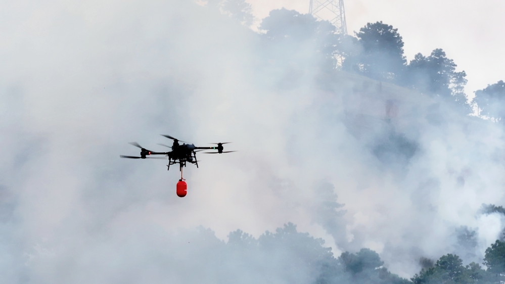 无人机挂载灭火弹进入火场压制火势。 李威 摄
