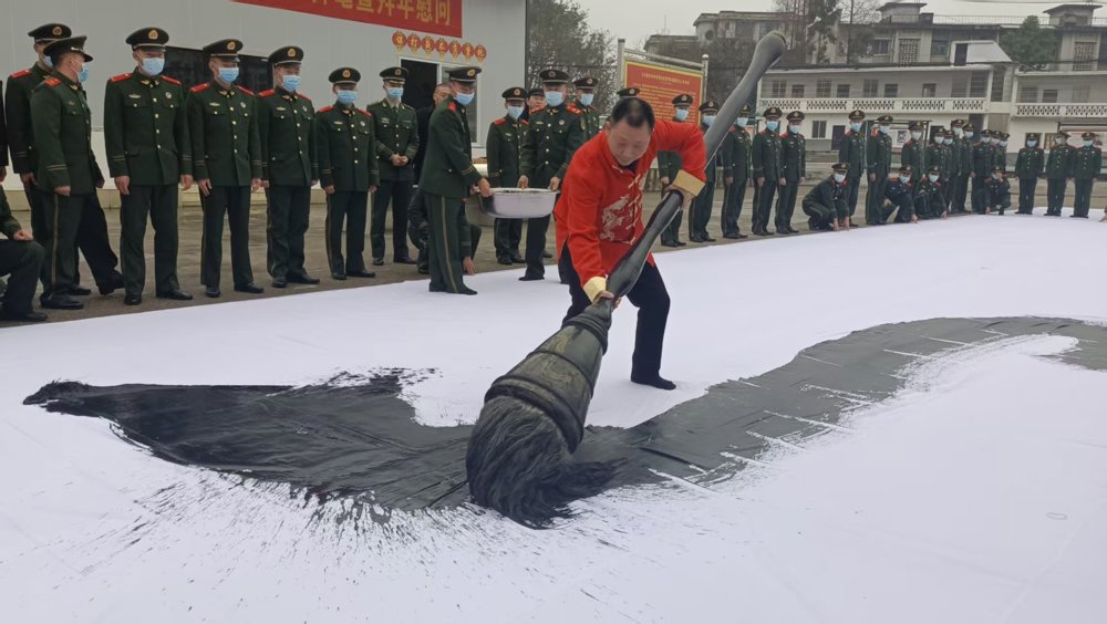 图为何文军正在用巨笔进行书法创作