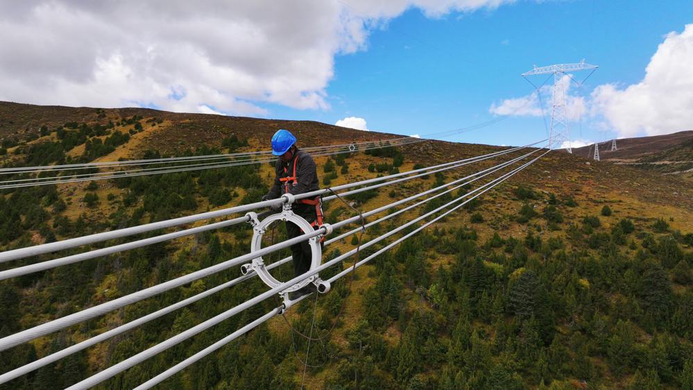 2024年10月1日，在甘孜州色炯玛山上，电力工人正在金沙江上游—湖北±800千伏特高压直流输电工程安装间隔棒。 张月 摄