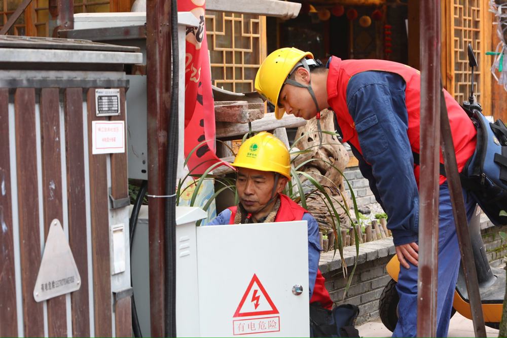 毛永平师傅（左一）和同事检查古街电力设备。（唐洪 摄）