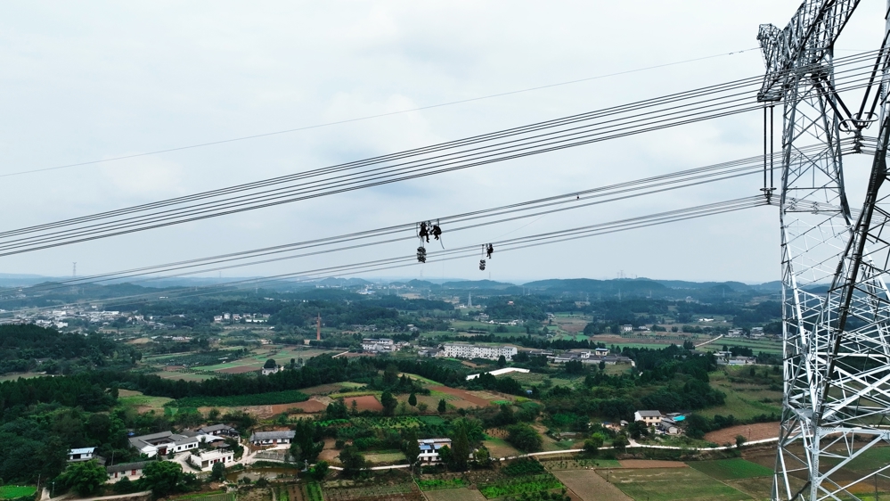 12月25日，在德阳市中江县，阿坝—成都东1000千伏特高压交流输电工程15标导线展放作业现场，国网四川电力工人正在安装间隔棒 国网四川建设公司供图