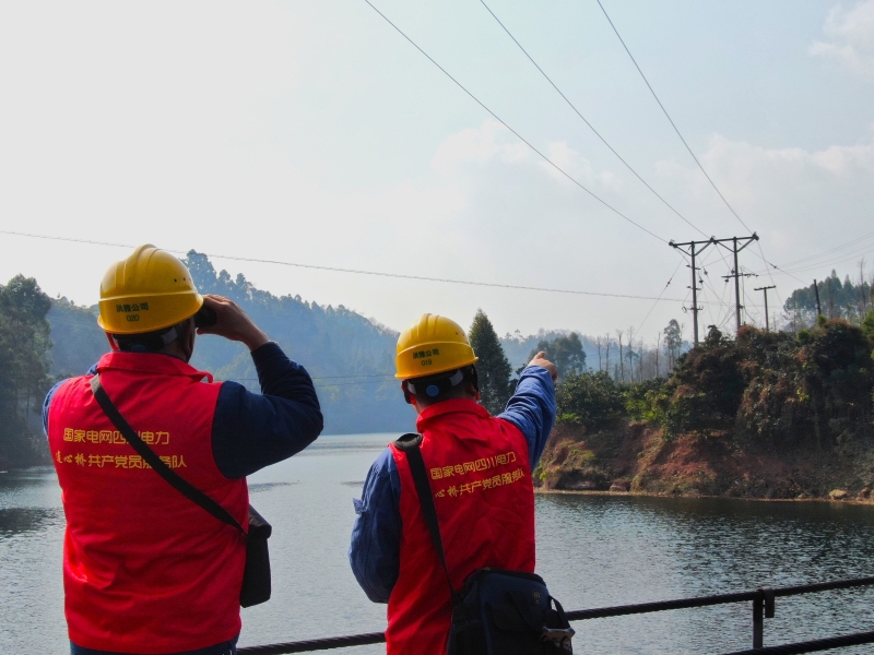 伍冰（左一）和同事在铁索桥上观察线路情况（赵浩洋 摄）
