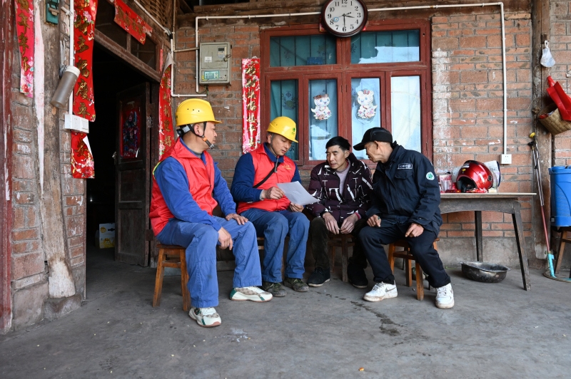 伍冰（右一）和同事向村民讲解春节安全用电事项（赵浩洋 摄）