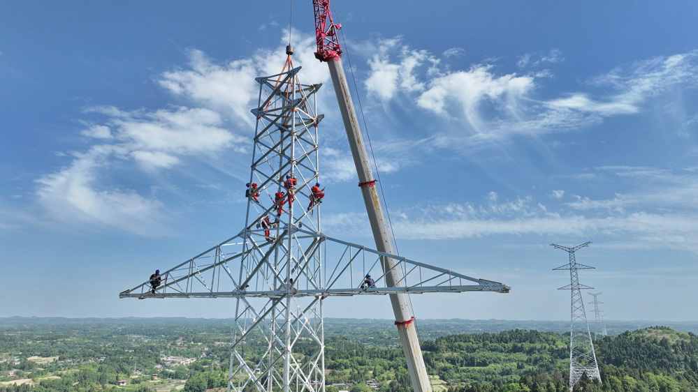 在简阳云龙镇庄园社区礼帽山，建设者正在进行空港—淮州双回500kV线路工程NC21铁塔组立。 陈翔 摄