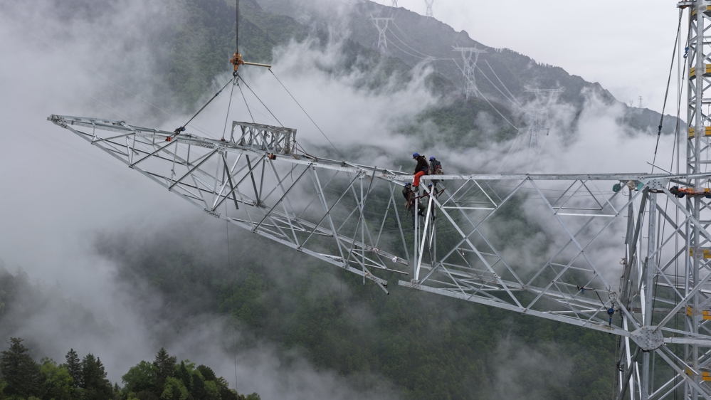 在阿坝藏族羌族自治州理县，阿坝—成都东1000千伏特高压交流工程的作业人员正在组立铁塔。 国网四川建设公司 供图