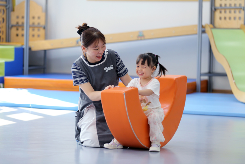 2026年9月2日，四川省乐山市市中区春华路西段一家婴幼儿托育中心，老师带领托育班的孩子一起玩摇摇月亮船游戏。