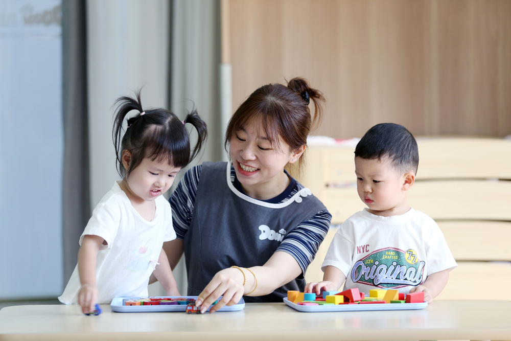 2026年9月2日，四川省乐山市市中区春华路西段一家婴幼儿托育中心，老师带领托育班的孩子一起玩积木拼搭益智游戏。 (1)
